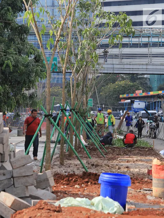 Pekerja menyelesaikan jalur pedestrian di Jalan Sudirman, Jakarta, Senin (2/7). Kelima stasiun tersebut yakni Stasiun Senayan, Stasiun Istora, Stasiun Bendungan Hilir, Stasiun Setiabudi dan Stasiun Dukuh Atas. (Liputan6.com/Arya Manggala)