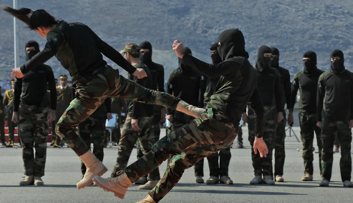 Pasukan perempuan Peshmerga bertarung melawan pria saat berlatihan dalam upacara kelulusan di Kota Soran, Irak, Rabu (12/2/2020). Latihan militer pasukan bersenjata Kurdi tersebut dilakukan sekitar 100 kilometer timur laut ibu kota otonomi wilayah Kurdi di Irak, Arbil. (SAFIN HAMED/AFP)