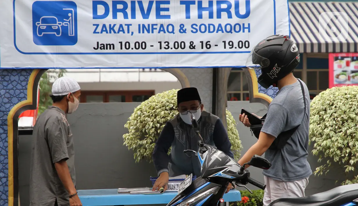 Petugas Amil Zakat melayani warga yang membayar zakat fitrah melalui sistem "drive thru" di Masjid Nurul Hidayah, Tanah Kusir, Jakarta, Selasa (19/5/2020). Layanan zakat "drive thru" selama pandemi COVID-19 ini diberlakukan dengan protokol kesehatan dan keselamatan. (Liputan6.com/ Johan Tallo)