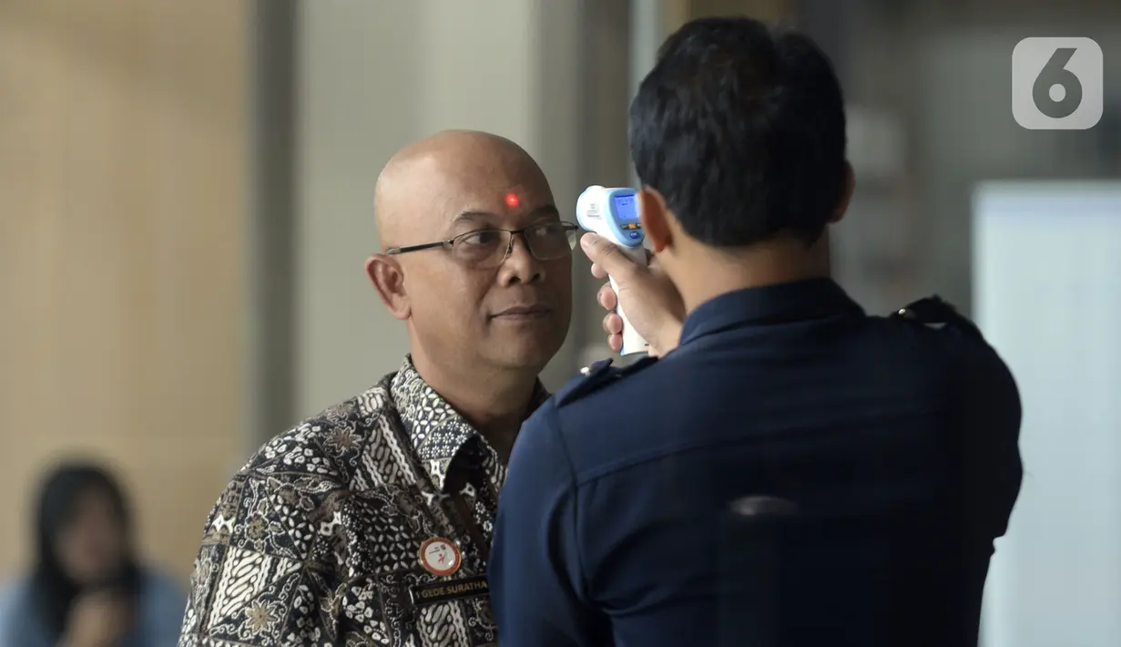 Petugas mengecek suhu tamu dan pegawai yang akan masuk ke Loby di Gedung KPK, Jakarta, Kamis, (12/3/2020). KPK menerapkan pengecekan suhu tubuh tersebut untuk mengantisipasi penyebaran virus corona atau covid-19. (merdeka.com/Dwi Narwoko)