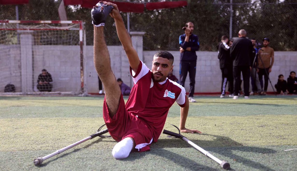 Ajang ini mendorong semangat inklusivitas dan sportivitas bagi penyandang disabilitas di Palestina. Tampak dalam foto, seorang penyandang disabilitas amputasi Palestina melakukan peregangan sebelum pertandingan sepak bola sebagai bagian dari ‘Hope Tournament’ atau Turnamen Harapan yang diselenggarakan oleh Asosiasi Deniz Feneri dan Asosiasi Sepak Bola Penyandang Disabilitas Palestina di Deir al-Balah, Jalur Gaza Tengah, pada 17 November 2025. (Bashar Taleb/AFP)