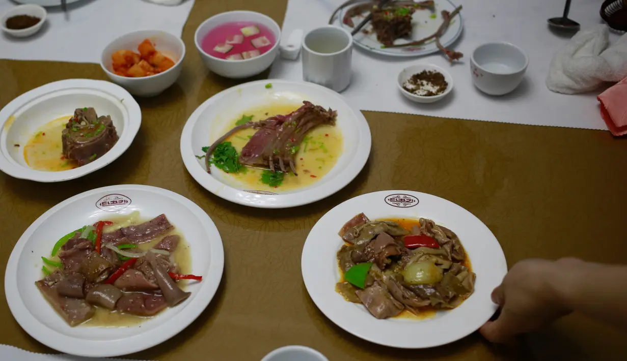 Pramusaji menyajikan hidang dari daging anjing  di restoran khusus anjing, Pyongyang House of Sweet Meat, Rabu (25/7). Masyarakat Korea percaya bahwa panas akan menyembuhkan panas sehingga mereka makan daging anjing saat cuaca panas. (AP/Dita Alangkara)