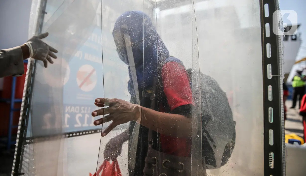 Seorang TKI Ilegal yang dipulangkan dari Malaysia keluar dari bilik disinfektan setibanya di Pelabuhan Tanjung Priok, Jakarta, Jumat (12/6/2020). Sebanyak 436 TKI Ilegal tersebut nantinya akan dipulangkan ke daerah asalnya di 22 provinsi. (Liputan6.com/Faizal Fanani)