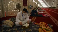 Pria Muslim (kiri) membaca Alquran saat beritikaf di Masjid Agung Faisal di Islamabad, Pakistan, Kamis (14/5/2020). Itikaf adalah berdiam diri di masjid dengan niat beribadah untuk mendekatkan diri kepada Allah swt pada sepuluh hari terakhir bulan Ramadan. (Aamir QURESHI/AFP)