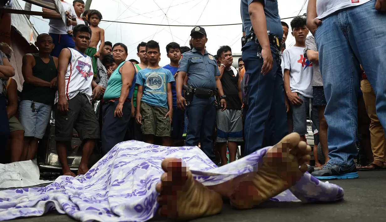 Dalam gambar yang diambil pada 10 November 2016, warga dan polisi berkumpul dekat jasad seorang wanita paruh baya berusia 47 tahun yang tewas ditembak oleh orang tak dikenal dalam perang melawan narkoba di Manila, Filipina. (TED Aljibe/AFP)