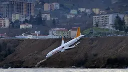 Pesawat maskapai Pegasus Airlines nyaris terperosok ke dalam laut saat mendarat di bandara Trabzon, Turki, Minggu (14/1). Pesawat itu tergeletak di tebing dengan bagian depannya hanya beberapa meter dari permukaan air Laut Hitam. (DHA-Depo Photos via AP)