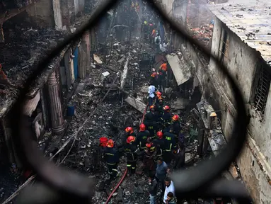 Petugas pemadam kebakaran terlihat di lokasi kebakaran di Dhaka (21/2). Setidaknya 69 orang tewas dalam kebakaran besar yang melanda gedung apartemen yang juga digunakan sebagai gudang bahan kimia di Bangladesh tersebut. (AFP Photo/Munir Uz Zaman)