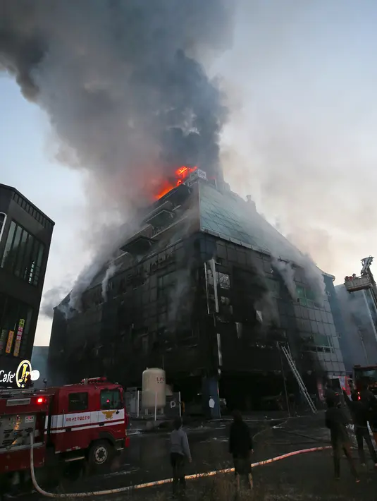 Api dan kepulan asap membumbung dari gedung pusat kebugaran berlantai delapan di Jecheon, Korea Selatan, Kamis (21/12). Terdapat sejumlah restoran dan fasilitas hiburan di gedung ini termasuk gym, tempat mandi umum dan golf dalam ruangan. (YONHAP/AFP)