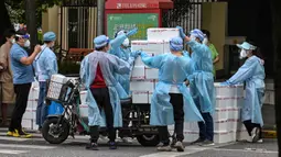 Pekerja yang mengenakan alat pelindung diri menumpuk kotak ke atas gerobak untuk dikirim saat perberlakuan lockdown karena virus corona COVID-19 di Distrik Jing'an, Shanghai, China, Rabu (18/5/2022). (Hector RETAMAL/AFP)