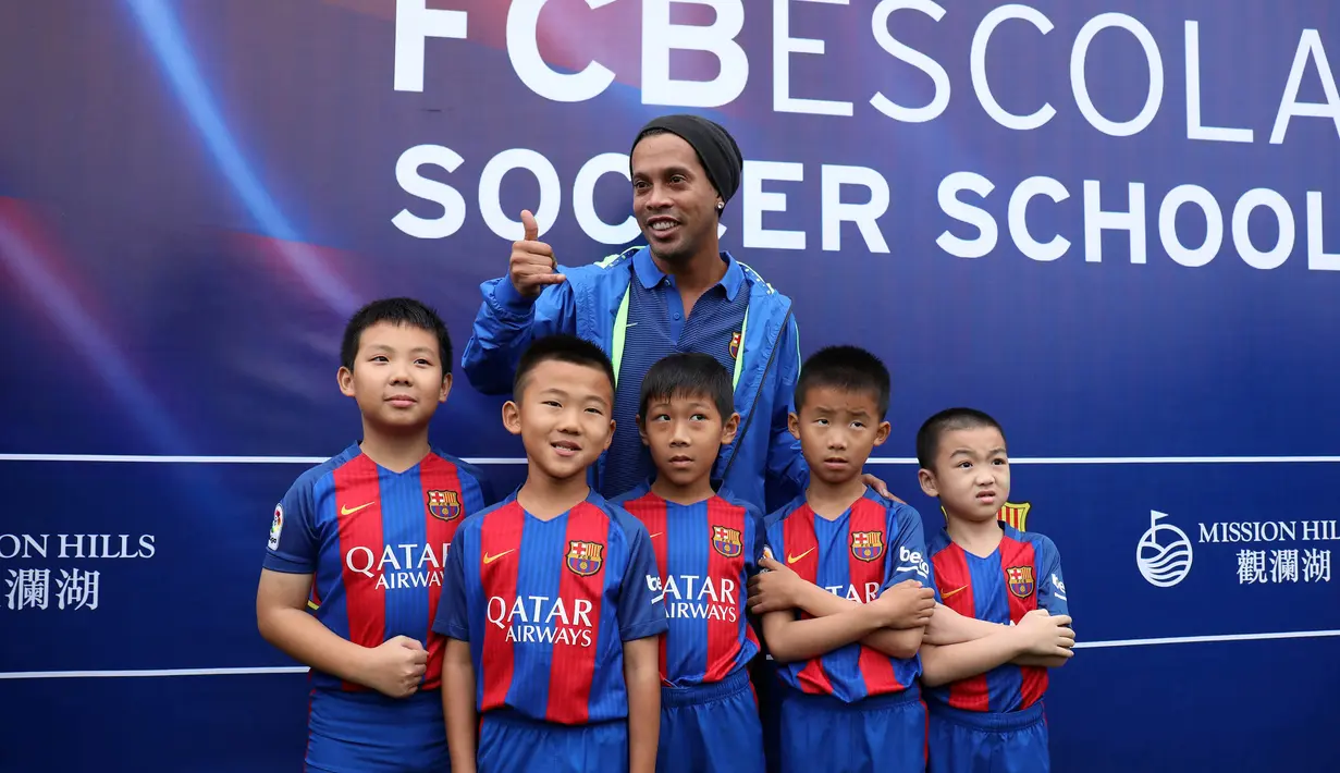 Ronaldinho mengakhiri sesi kunjungannya dengan foto bersama anak-anak peserta akademi Barcelona. (AFP/Handout)