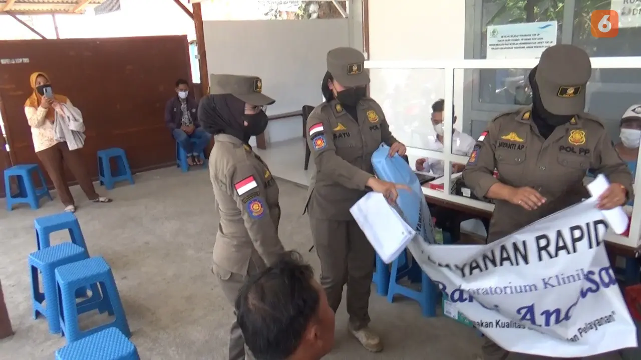 Satpol PP Banyuwangi Menurutkan Papan Nama Gerai Rapid Test Antigen Tidak Berijin. (Hermawan Arifianto/Liputan6.com)