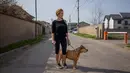 Silvia Rad (34) berpose dengan anjingnya Sa'id (12) saat perjalanan di Bucharest (28/3/2020). Undang-undang militer, yang disahkan pemerintah Rumania untuk mengurangi penyebaran virus corona, menyatakan berjalan bersama anjing adalah salah satu  kegiatan yang masih diizinkan. (AFP/Andrei Pungovschi)