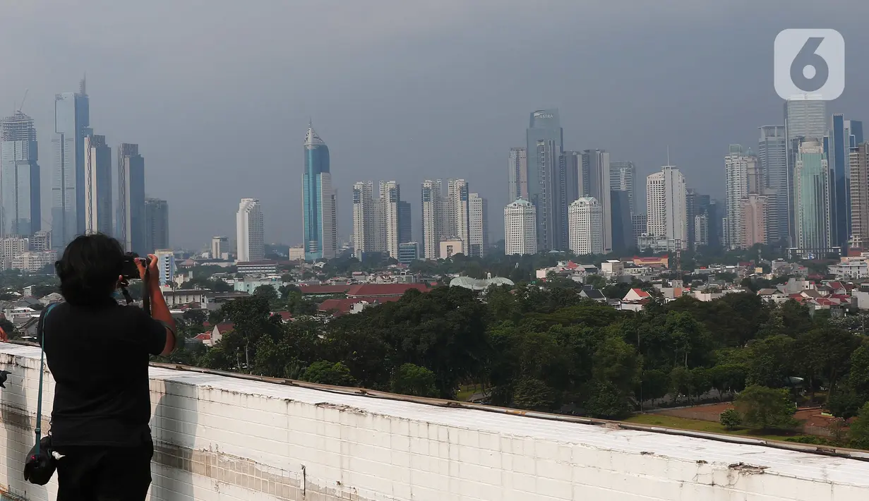 Seseorang mengambil gambar suasana gedung bertingkat di kawasan Jakarta, Jumat (17/6/2022). Jakarta meneruskan posisinya di jajaran atas kota berkualitas udara buruk di dunia hari ini, Jumat 17 Juni 2022, setelah kemarin mencatat hal serupa. (Liputan6.com/Angga Yuniar)