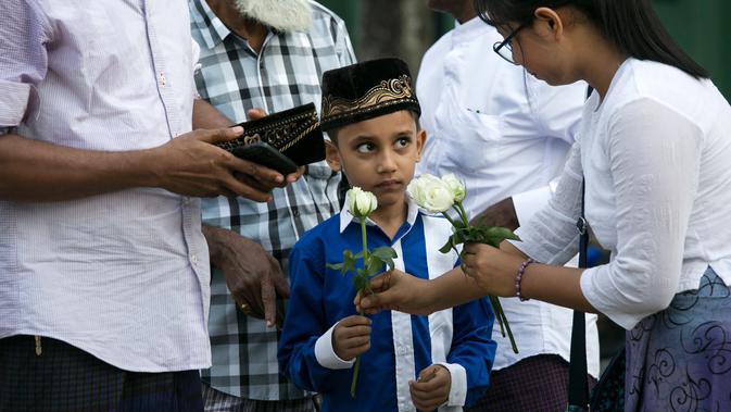 Umat Buddha Myanmar membagikan mawar putih kepada bocah Muslim setelah melaksanakan salat Id pada perayaaan Idul Fitri di kota Than Lyin, Yangon, Rabu (5/6/2019). Tindakan itu dilakukan beberapa minggu setelah kelompok garis keras berusaha menghapuskan doa selama bulan Ramadhan. (Sai Aung MAIN/AFP)