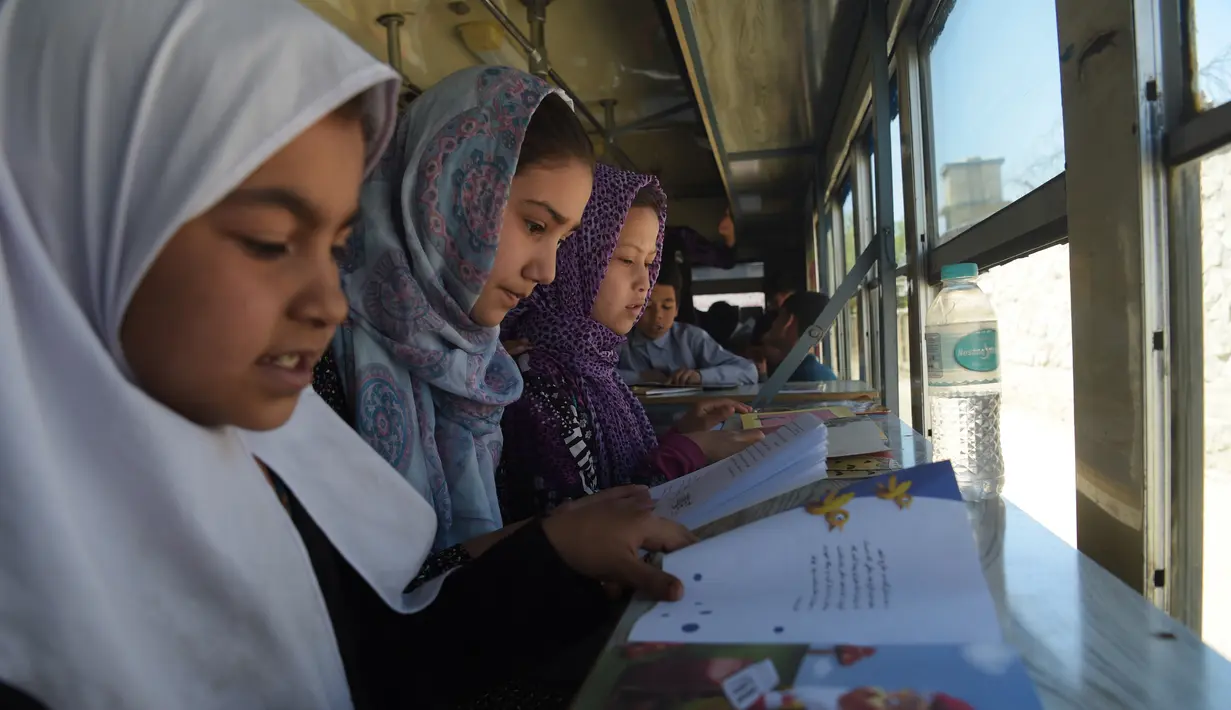 Anak-anak Afghanistan membaca buku dalam bus yang dijadikan perpustakaan keliling di Kabul, 4 April 2018. Perpustakaan keliling itu tidak melintasi jalan-jalan utama yang dilalui dan daerah-daerah menghindari kelompok militan di Kabul. (AFP/Shah MARAI)