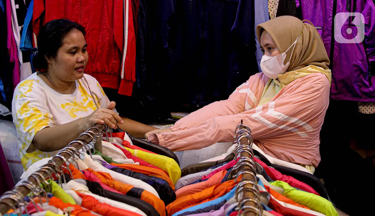 Calon pembeli menjajal pakaian impor bekas di Pasar Senen, Jakarta, Kamis (9/3/2023). Larangan impor baju bekas tercantum dalam Peraturan Menteri Perdagangan (Permendag) No.18/2021 tentang Barang Dilarang Ekspor dan Barang Dilarang Impor. (Liputan6.com/Faizal Fanani)
