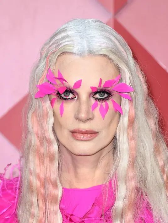 Kristen McMenamy memilih bulu mata merah muda neon yang tebal. Ini merupakan pilihan sempurna untuk rambut putih panjangnya.