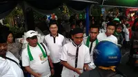 Gelandang Bhayangkara Surabaya United, Muhammad Hargianto membagikan takjil kepada pengendara motor yang melewati kawasan Taman Bungkul, Surabaya, Kamis (16/6/2016). (Bola.com/Fahrizal Arnas)