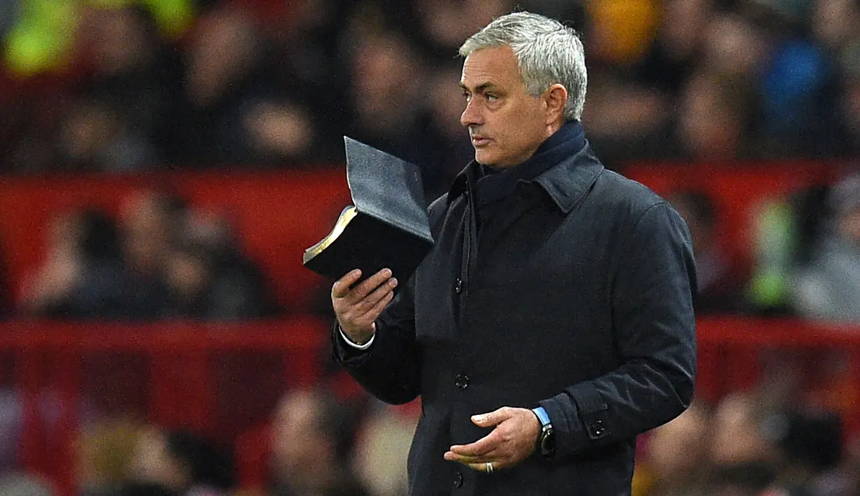 Pelatih Tottenham Hostpur, Jose Mourinho membawa buku saat pertandingan melawan Manchester United pada lanjutan Liga Inggris di Old Trafford, Rabu (4/12/2019). Mourinho gagal mengalahkan Manchester United mantan klub yang pernah dilatihnya. (AFP Photo/Oli Scarff)