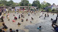 Sejumlah warga ngubek empang atau mencari ikan di dalam kolam pada rangkaian lebaran Depok di Kecamatan Bojongsari, Kota Depok. (Liputan6.com/Dicky Agung Prihanto)