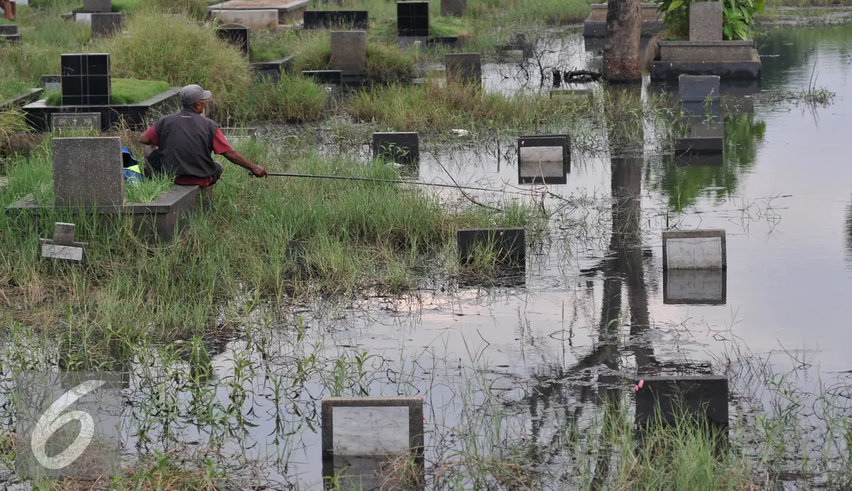 Seorang warga memancing ikan di Taman Pemakaman Umum (TPU) Tanah Kusir, Jakarta Selatan, Jumat (26/8). Warga memanfaatkan Banjir yang merendam makam di kawasan tanah kusir ini terjadi akibat luapan Sungai Pesanggrahan. (Liputan6.com/Johan Tallo)