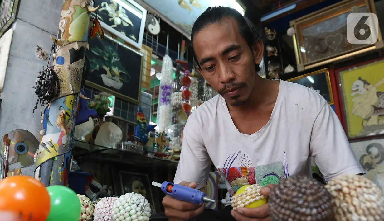 Perajin menyelesaikan pembuatan kerajinan dari kerang di Kawasan Ancol Jakarta, Kamis (14/11/2019). Limbah cangkang kerang itu dimanfaatkan Sugiro (39) untuk dibuat menjadi berbagai kerajinan dengan harga jual mulai Rp 20ribu hingga jutaan tergantung tingkat kesulitan. (Liputan6.com/Herman Zakharia)