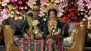 Fitri pun mengenakan aksesori, besar-besar warna gold dari anting, kalung, dan gelangnya. Keduanya pun duduk di pelaminan dekorasi bunga warna-warna meriah. [@yuniantiefendy]