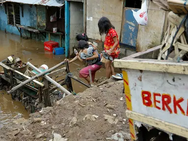 Warga melintasi banjir yang mulai memasuki belasan rumah warga di RT 11/ RW 07 sejak pukul 01.00 WIB dini hari tadi, Jakarta, Senin (16/11/2015). Ketinggian air mencapai 3 meter saat subuh dan merendam puluhan rumah. (Liputan6.com/Yoppy Renato)