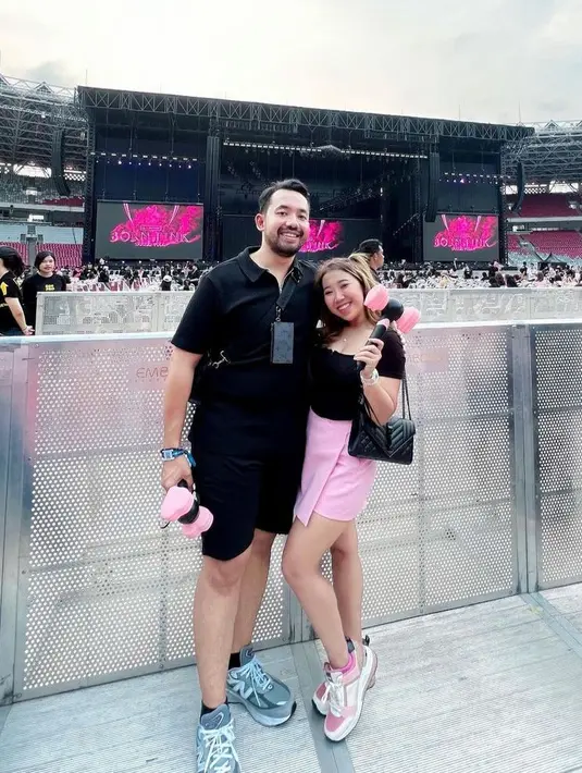 Kiky Saputri mengenakan black top dan mini skirt warna pink saat nonton konser bareng sang suami. @kikysaputri.