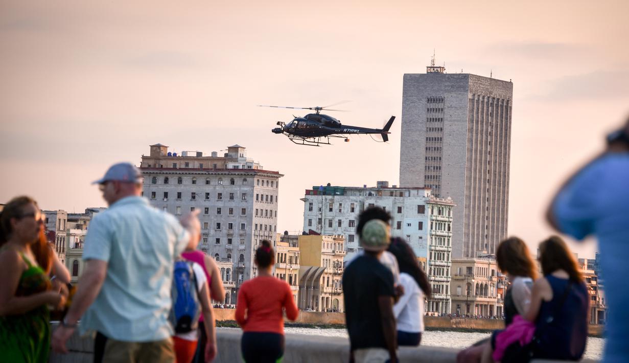 Sejumlah warga melihat helikopter milik Universal Studios Hollywood saat mengambil gambar selama pembuatan film Fast and Furious 8 di Havana, Kuba (28/4). (AFP PHOTO/ADALBERTO ROQUE)