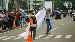 Personel gabungan dari unsur polisi hingga Satpol PP mengatur lalu lintas di kawasan zebra cross Dukuh Atas, Jakarta, Rabu (27/7/2022). Mereka dikerahkan untuk memantau kegiatan peragaan busana Citayam Fashion Week (CFW) guna meminimalisir terjadinya kriminalitas, kemacetan, hingga parkir liar. (Liputan6.com/Faizal Fanani)