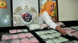 Petugas menata barang bukti narkoba saat rilis barang bukti di Mako Ditnarkoba Mabes Polri, Jakarta, Jumat (19/2). Petugas menangkap 7 orang tersangka sindikat narkotika internasional dan menyita 40 ribu butir ekstasi. (Liputan6.com/Yoppy Renato)