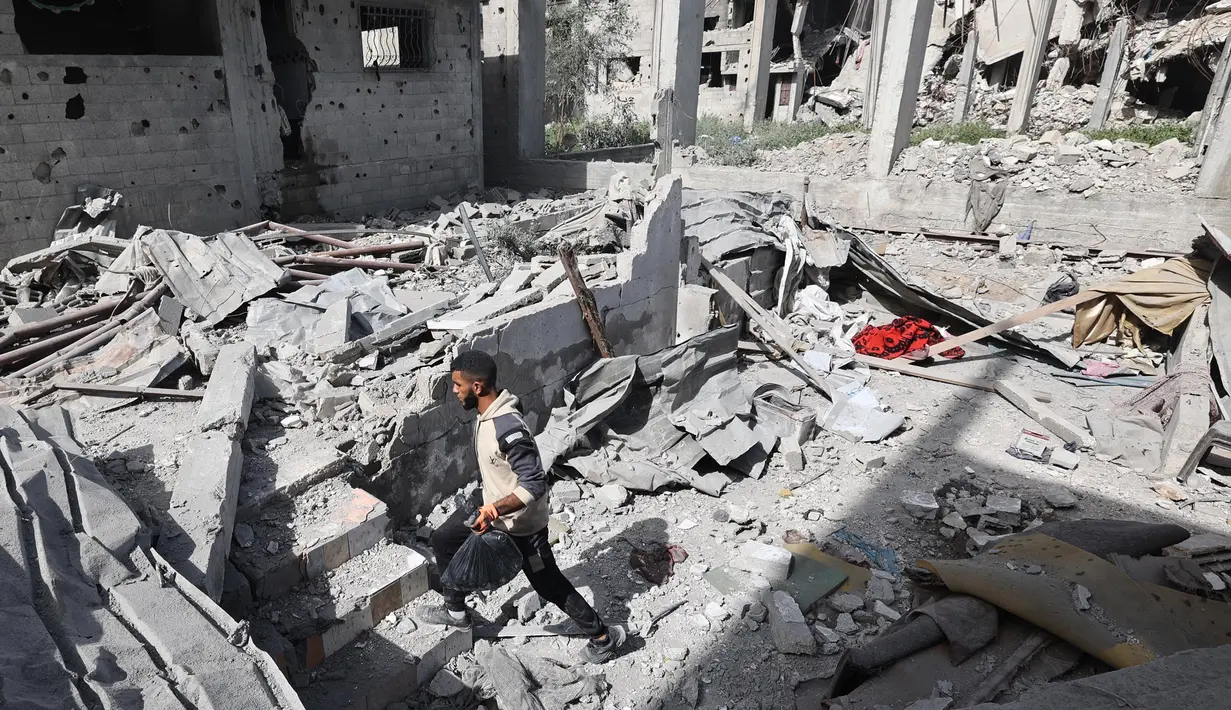 Seorang pria Palestina berjalan di antara reruntuhan bangunan di daerah yang menjadi sasaran serangan Israel di Khan Yunis di Jalur Gaza selatan, pada 2 April 2025. (Eyad BABA/AFP)