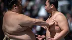 Para pegulat sumo melakukan pemanasan sebelum "turnamen sumo besar nazar", sebuah pameran sumo seremonial, di halaman Kuil Yasukuni di Tokyo pada 17 April 2023. (AFP/Philip Fong)