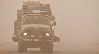 Sebuah truk melaju melalui badai pasir Musim Semi di kota Nasiriyah, di provinsi Dhi Qar, Irak selatan (5/5/2022). Irak kembali diselimuti lapisan jingga tebal karena mengalami serangkaian badai debu terbaru yang semakin sering terjadi. (AFP/Asaad Niazi)