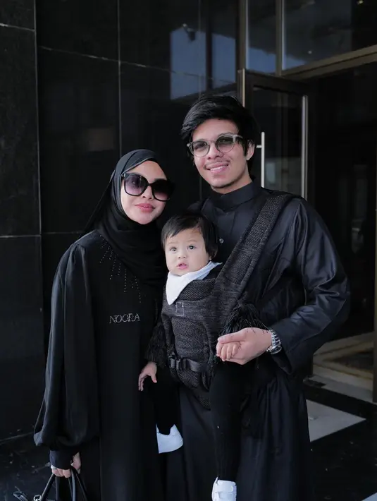 <p>Aurelie Hermansyah dan Atta Halilintar baru saja menjalankan ibadah umrah bersama. Yang menarik adalah keduanya membawa sang buah hati Ameena dalam perjalanan ibadah ini. Dalam potret ini, ketiganya kompak mengenakan outfit serba hitam dengan Atta menggendong Ameena di depan. Foto: Instagram.</p>