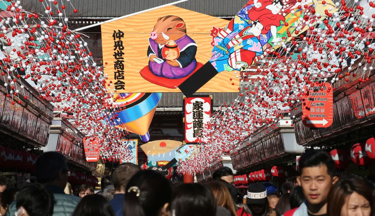 Pejalan kaki melintas di bawah dekorasi shio babi tanah yang mengarah ke kuil Buddha Asakusa Sensoji di Tokyo, Jepang, Kamis (27/12). Tahun babi tanah 2019 akan penuh sukacita cocok untuk persahabatan dan cinta semua shio. (AP Photo/Koji Sasahara)