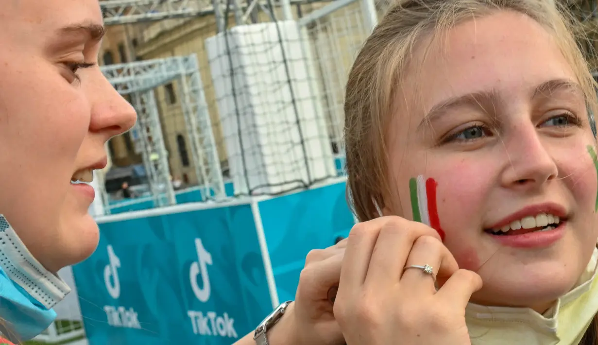 Para suporter wanita ini mendukung Timnas Italia dengan berbagai cara, salah satunya riasan wajah berbentuk bendera negara Timnas kesayangan mereka. (Foto: AFP/Andreas Solaro)
