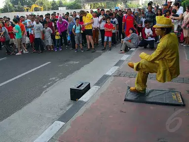 Seorang manusia patung tampak melakukan aksi 'bangku setan' Minggu (18/05/14) di Kawasan Sudirman, Jakarta (Liputan6.com/Miftahul Hayat)