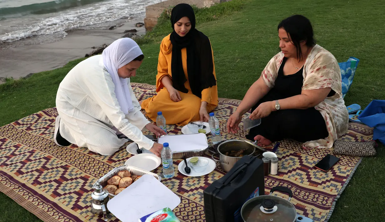 Perempuan dari Mesir dan Maroko berkumpul untuk berbuka puasa selama bulan suci Ramadhan di pantai di Muscat, Oman pada 12 April 2022. Umat islam di seluruh dunia saat ini tengah melaksanakan bulan Ramadhan dan berpuasa selama satu bulan. (MOHAMMED MAHJOUB / AFP)