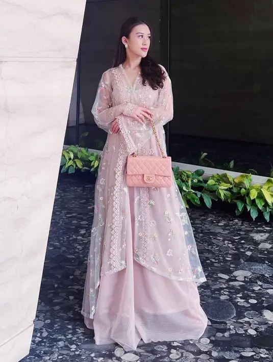 Mengenakan dress panjang model lace warna pink, Kusuma Puteri juga membawa tas warna senada dari Chanel dengan tali rantai yang khas. [@kusumaputeri]