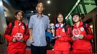 Pemain Timnas Indonesia, Laita Roati (kiri), Viny Silfianus (kedua kanan), Reva Octaviani (kanan), dan pelatih Satoru Mochizuki (kedua kiri) berpose dengan membawa trofi Piala AFF Wanita 2024 dan penghargaan individu (kiper terbaik dan pemain terbaik) saat mendarat di Gedung VVIP Terminal 3 Bandara Soekarno Hatta, Tangerang, Jumat (06/12/2024). (Bola.com/Bagaskara Lazuardi)