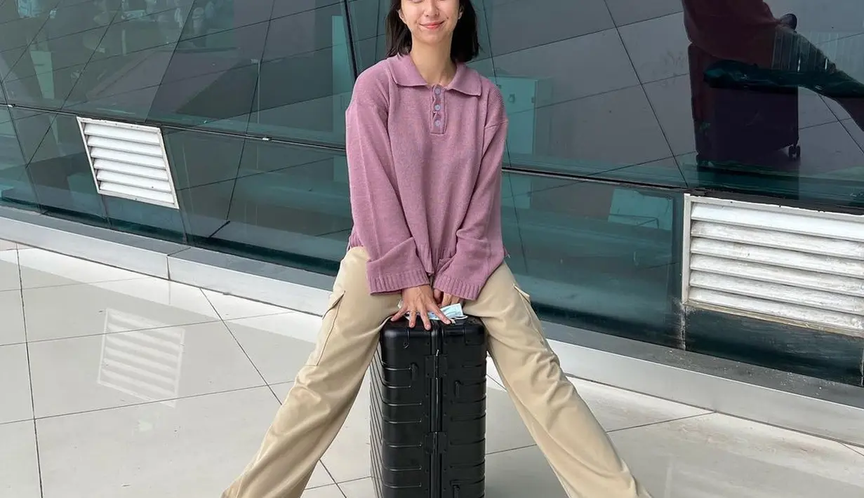 Wanita yang kerap disapa Clay itu terlihat gembira menunggangi koper setiap kali liburan. Seolah belum lengkap rasanya jika tak berpose bersanding dengan kopernya.  (Liputan6.com/IG/@clairineclay).