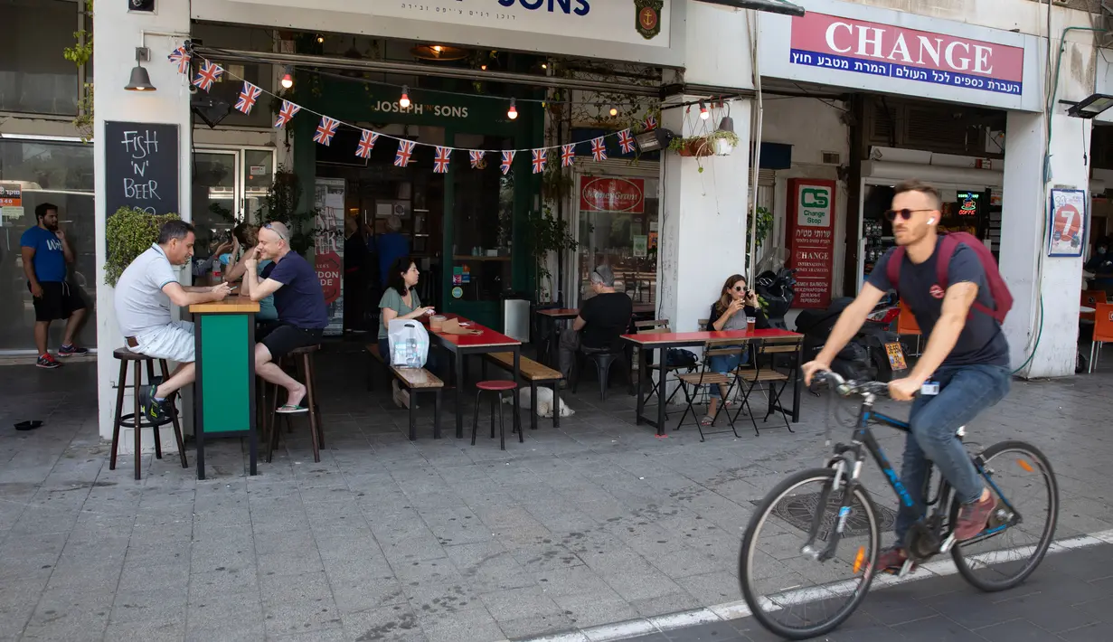 Pengunjung makan di luar di sebuah restoran di Tel Aviv, Israel pada Rabu (27/5/2020). Setelah lebih dari dua bulan ditutup untuk membendung penularan virus corona, restoran hingga kafe di Israel diizinkan dibuka kembali hari Rabu, 27 Mei. (AP Photo/Sebastian Scheiner)
