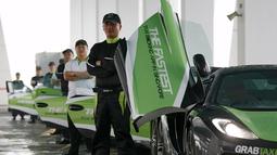 Pengemudi GrabTaxi berpose saat melakukan pemotretan dengan tujuh mobil mewah untuk pemotretan sebelum beroperasi di Singapura, Selasa (15/9). Mobil-mobil mewah itu akan melayani penumpang secara gratis selama musim balapan F1. (REUTERS/Edgar Su)