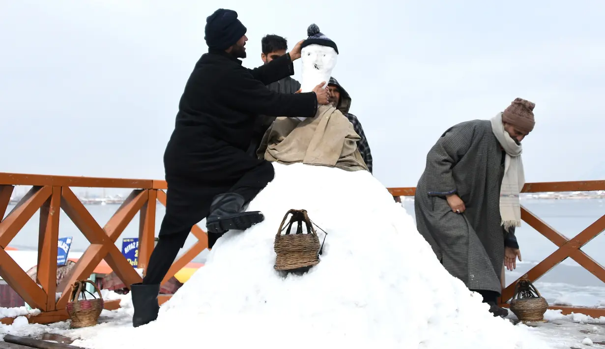 Sejumlah pria Kashmir membuat boneka salju di tepi Danau Dal setelah salju turun di Srinagar, India bagian utara, Sabtu (5/1). Wilayah Kashmir mengalami salju selama beberapa hari yang mengakibatkan terputus jalan raya Jammu-Srinagar (TAUSEEF MUSTAFA/AFP)