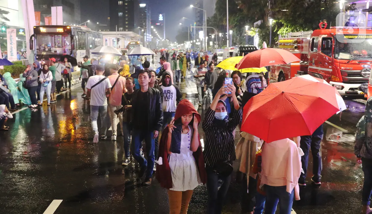 Masyarakat mulai memadati car free night di kawasan Thamrin, Jakarta, Selasa (31/12/2019). Meski diguyur hujan masyarakat mulai memadati kawasan tersebut untuk menikmati malam pergantian tahun 2019. (Liputan6.com/Angga Yuniar)