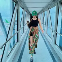 Siapa bilang kain batik tak bisa digunakan secara kasual? Lihat airport look ala Yura Yunita di sini. Ia mengenakan tank top hitam, dipasangkannya dengan kain batik bernuansa hijau yang senada dengan topi yang dikenakannya. Foto: Instagram.