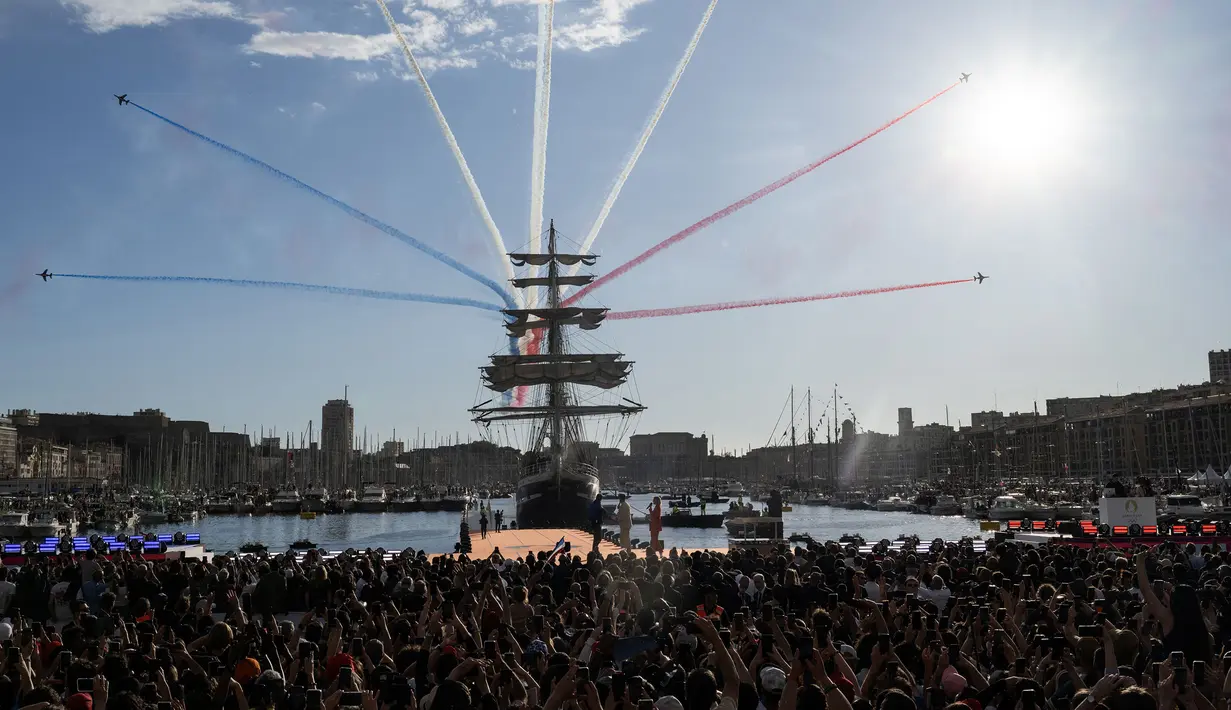 Tim terbang akrobatik elit Angkatan Udara Prancis, Patrouille de France (PAF) melakukan manuver di atas kapal abad ke-19 bernama Belem saat upacara penyambutan kedatangan api Olimpiade dan Paralimpiade Paris 2024 di Vieux-Port (Pelabuhan Tua) Marseille, Pranci, Rabu (08/05/2024) waktu setempat. (AFP/Nicolas Tucat)