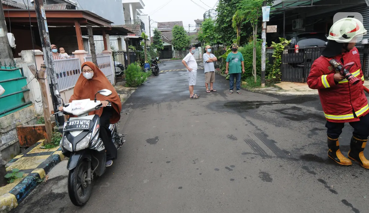 Warga melintas saat petugas Damkar bersiap menyemprotkan cairan disinfektan pada pemukiman RW 21 Keluarahan Benda Baru, Tangerang Selatan, Banten, Kamis (1/7/2021). Penyemprotan dilakukan pada kawasan zona merah dimana di wialayah ini 46 warga terpapar Covid-19. (merdeka.com/Arie Basuki)